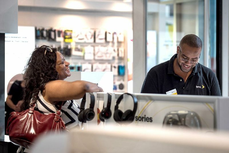 A Sprint Corp. employee assists a customer at the company’s store inside the James R. Thompson Center in Chicago in July.
