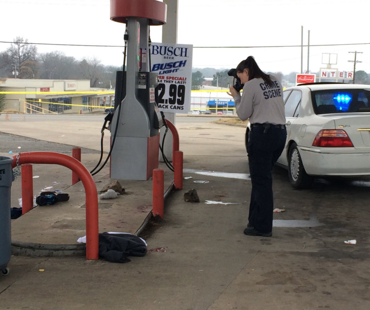 A Little Rock Police Department crime scene investigator takes photos at a gas station after a shooting there Sunday afternoon.