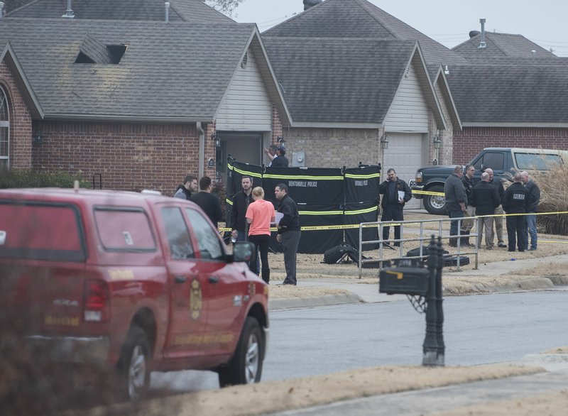 Bentonville police and fire investigators interview neighbors Monday at 1901 SW E St. in Bentonville. A man was found dead inside the home after a fire was reported at 7:53 a.m., according to police.