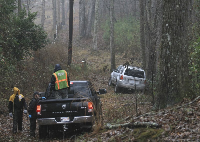 Arkansas Democrat-Gazette/BENJAMIN KRAIN A wrecker crew prepares to remove a stolen vehicle from woods off Chicot Road in Saline County on Monday morning. The SUV was stolen at a Little Rock gas station shortly after 7 a.m. at 7700 Scott Hamilton Road. A 1-year-old and a 6-year-old were inside the vehicle but were dropped off unharmed in a residential area a short time later.