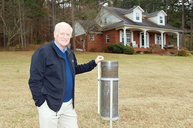 Danville Mayor Phil Moudy stands in his front yard next to the gauge he uses to measure rainfall, which he reports to the National Weather Service in North Little Rock. Starting with his grandfather in 1945, the Moudy family has volunteered for the National Weather Service’s Cooperative Weather Observer Program.