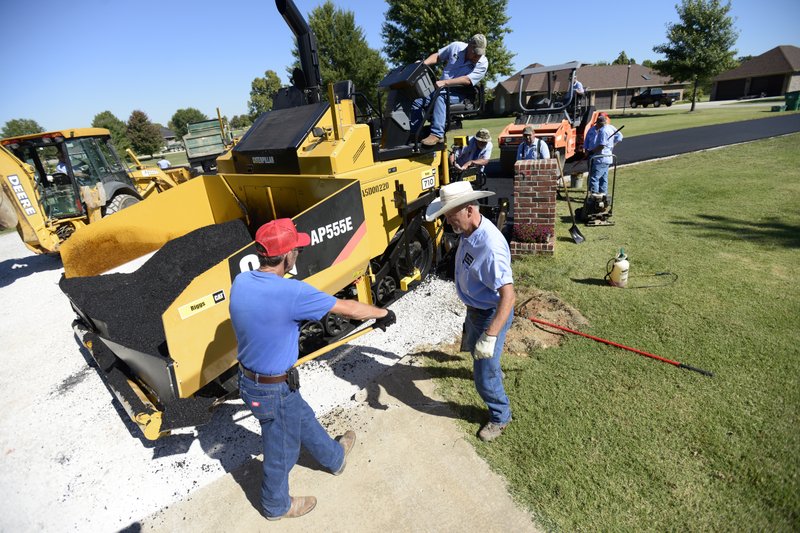 Crews with Springdale Public Works Department pave a road Thursday, Oct. 10, 2013 in Springdale. Benton County's roads department has now invested in similar technology; an asphalt paving machine to recycle road surfaces and a high-tech positioning system.