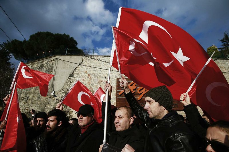 People wave Turkish flags as they march Tuesday to protest the New Year’s nightclub attack and in memorial to the victims in Istanbul.