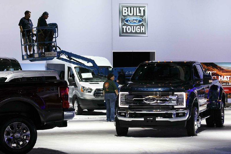 Workers operate a lift near Ford Motor Co. pickups displayed at the company’s booth at the Los Angeles Auto Show in November. After seven straight years of sales gains, U.S. auto sales are expected to drop off in 2017, analysts said Wednesday. 