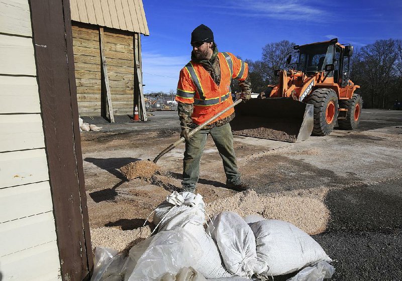 Arkansas Highway and Transportation Department employee Derrick Burrus works Wednesday shoveling salt mixture into a storage barn in south Little Rock after receiving a new load of the anti-icing material earlier in the day.