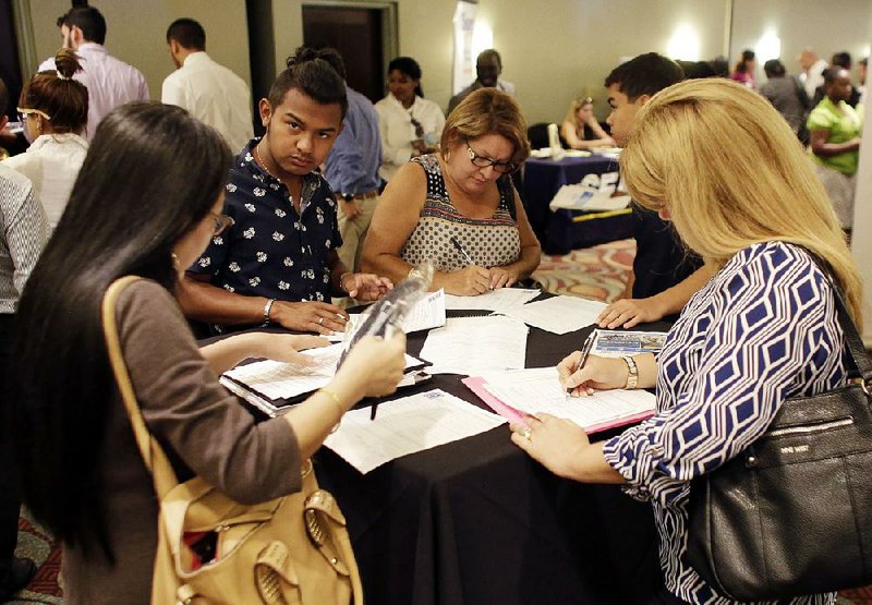 Job seekers fill out applications at a career event in July in Miami Lakes, Fla. The low level of applications for jobless benefits suggests employers likely are looking to add workers, analysts say.