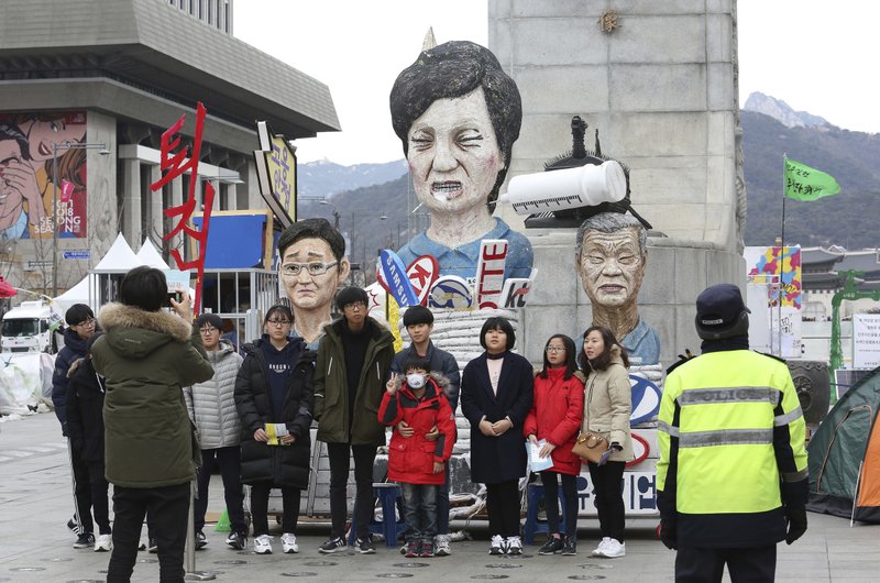People pose for photos in front of effigies of impeached South Korean President Park Geun-hye, center, Hyundai Motor Co. Chairman Chung Mong-koo and Samsung Electronics Co. Vice Chairman Lee Jae-yong, left, in Seoul, South Korea, Thursday, Jan. 5, 2017. South Korean lawmakers on Thursday accused Park of &quot;broadly and gravely&quot; violating the constitution as the country's Constitutional Court began hearing oral arguments in her impeachment trial. 