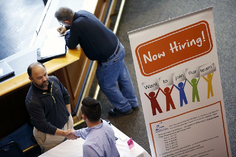 A recruiter greets a job applicant during a career fair in May in Louisville, Ky. The Labor Department said Friday that more people began looking for work, which raised the December unemployment rate to 4.7 percent. 