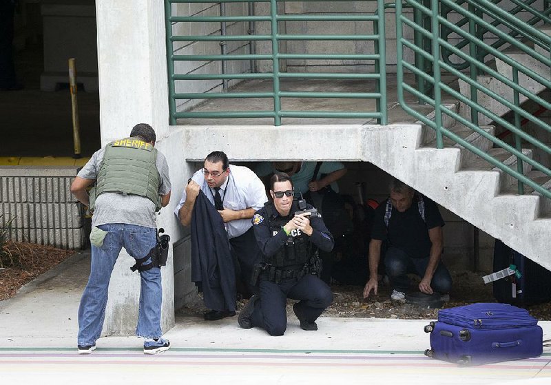 Law enforcement officials shield civilians outside a garage at Fort Lauderdale-Hollywood International Airport in Fort Lauderdale, Fla., after gunfire broke out Friday.