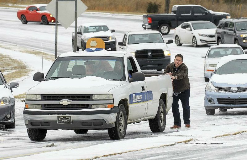 Chad Denman helps push motorists up Crystal Hill Road near Interstate 430 in North Little Rock after several vehicles got stuck on the ice-slicked road Friday morning. More photos are available at arkansasonline.com/galleries.