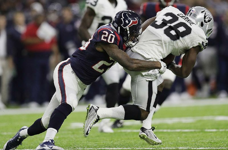 Houston defensive back Don Jones (left) takes down Oakland kick returner T.J. Carrie in the second half of an AFC wild-card game Saturday. The Texans held the Raiders to 203 yards of total offense and pulled way for a 27-14 victory.