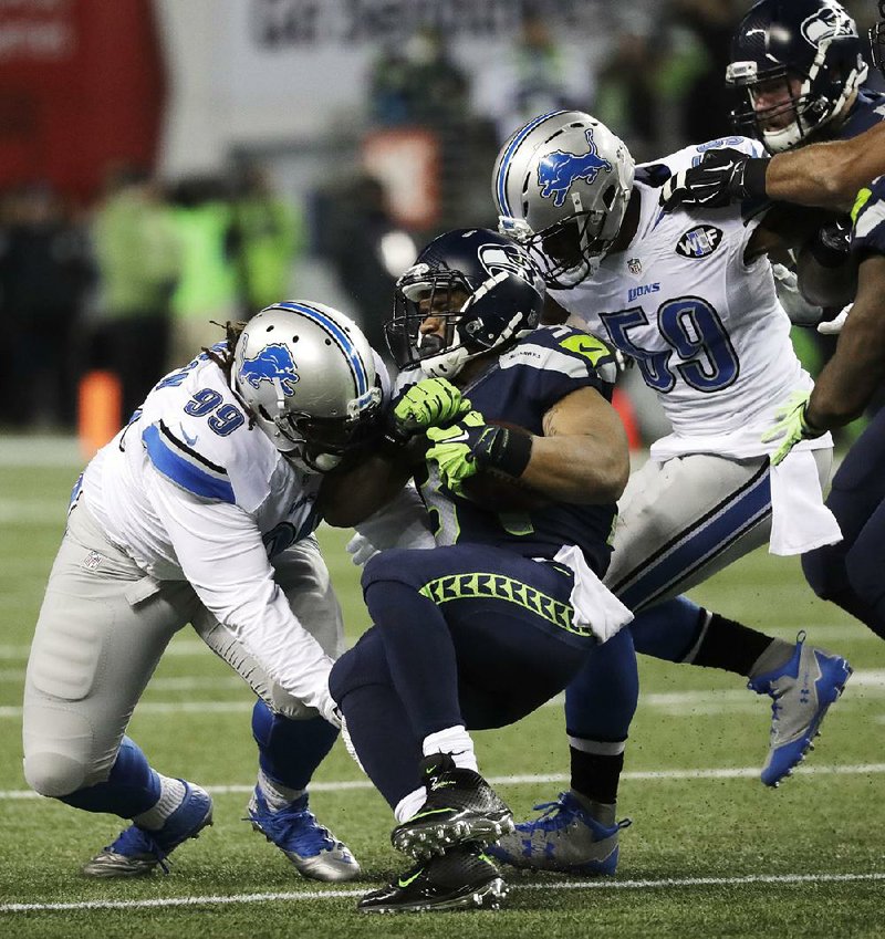 Seattle Seahawks running back Thomas Rawls (center) is tackled by Detroit Lions defensive tackle Khyri Thornton (99) and linebacker Tahir Whitehead (59) during the first half of Saturday’s NFC wild-card game in Seattle. Rawls finished with 161 yards and 1 touchdown on 27 carries in Seattle’s 26-6 victory.