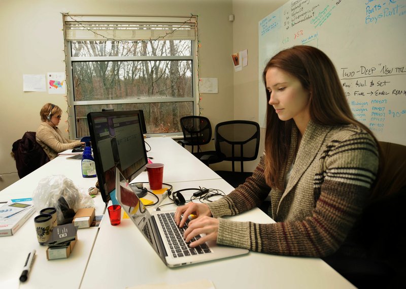 Amy Zubrzycki (right), vice president of customer service for Menguin, works with customers over a laptop computer Thursday alongside Jessica Phillippe, a customer service representative, at the company’s office in Fayetteville. The company, which provides online tuxedo rentals and support for formal gatherings, plans to move to a larger location in response to the company’s growth.