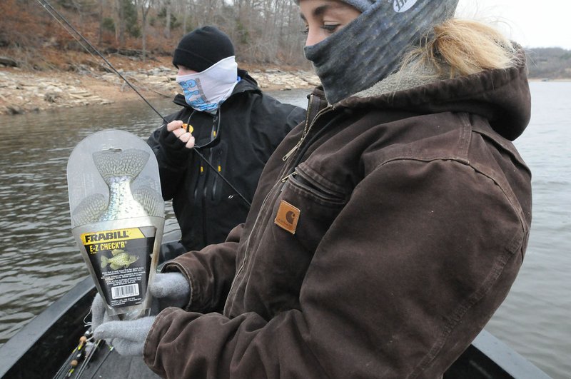 Tiffany Usrey checks the length of a crappie to make sure it is at least 10 inches and big enough to keep. The crappie is one of several she and her husband, Payton Usrey (left) caught during a chilly day of fishing at Beaver Lake.