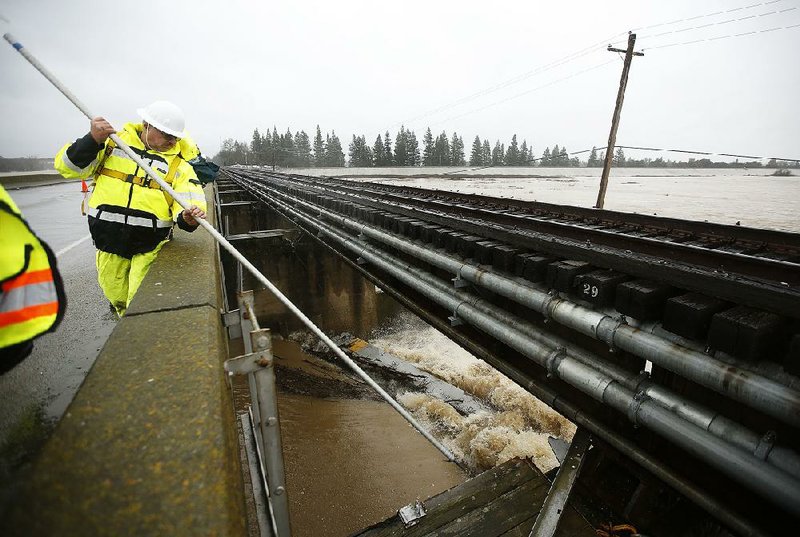 A worker opens a spill gate Tuesday in West Sacramento, Calif., to relieve flooding on the Sacramento River.
