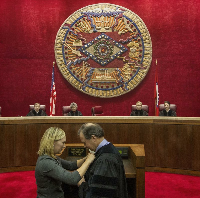 Arkansas Supreme Court Chief Justice Dan Kemp is robed by his daughter Erin Brogdon during an oath of office ceremony in 2017 in the courtroom. 