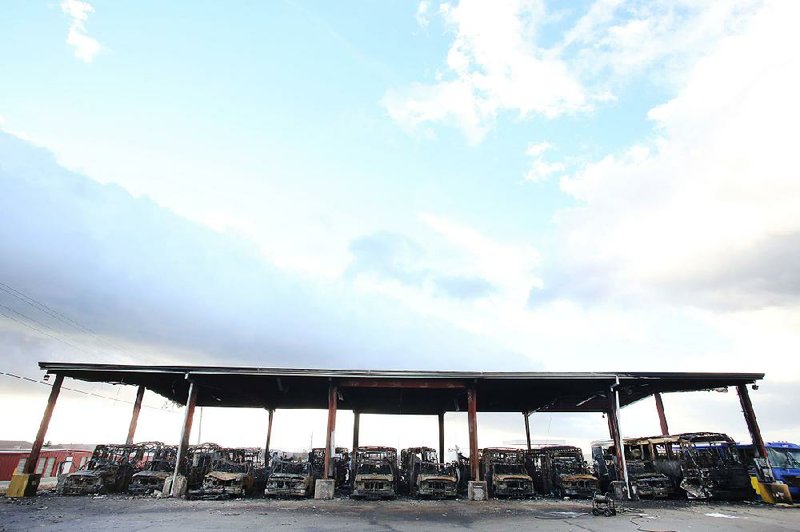 The remains of destroyed buses are visible Tuesday under the bus canopy at Ozark Regional Transit in Springdale. Twenty buses were destroyed in a fire that started around 1 a.m.