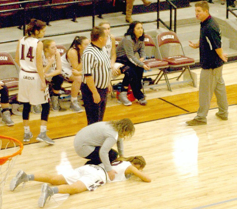 Photo by Mark Humphrey/Enterprise-Leader Lincoln head girls basketball coach Brian Davenport (right) pleads his case to a referee while assistant coach Stephanie Howard examines her daughter, Natalie, who had her legs taken out while trying to pass and fell head first. No foul was called against Shiloh Christian for the trip which resulted in a turnover and a touch foul against Lincoln at the other end. Lincoln was assessed a technical foul and Shiloh took a 47-45 lead from the free thows on their way to getting a 57-55 overtime win.