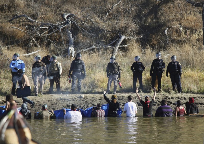 The Associated Press WATER PROTECTORS: Protesters demonstrating against the expansion of the Dakota Access Pipeline wade in cold creek waters confronting local police on Nov. 2, 2016, near Cannon Ball, N.D.