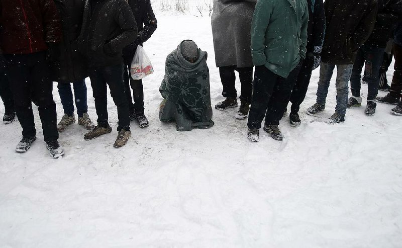Migrants wait in line for food in the snow Wednesday at an abandoned warehouse in Belgrade, Serbia.