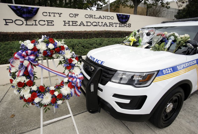 A wreath and flowers surround Orlando police shooting victim, officer Debra Clayton's patrol car, in front of police headquarters, Tuesday, Jan. 10, 2017, in Orlando, Fla. 