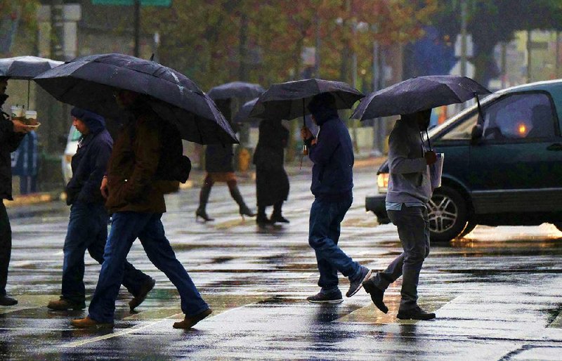 Pedestrians walk through soggy downtown streets Thursday in Los Angeles as California gets another round of rain. With all of the recent rainfall, more than 40 percent of the state has emerged from drought, officials said. 