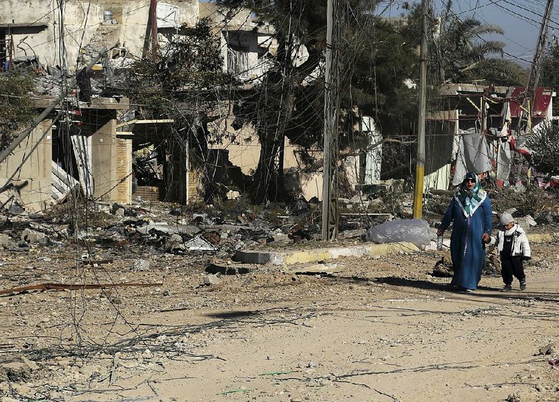 A woman and boy Thursday pass bombed-out buildings on the eastern side of Mosul, Iraq, as peacetime activities begin to return to the area.