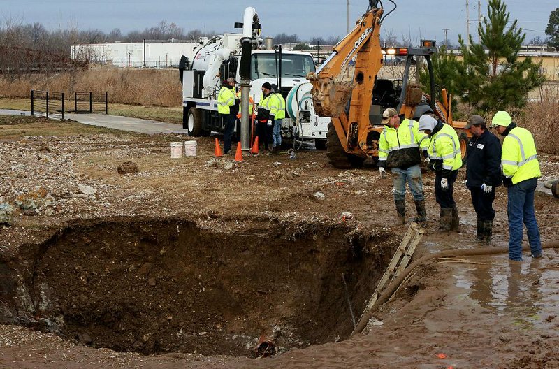 Springdale Water Utilities personnel drain the area around a 36-inch waterline that broke early Thurs day, disrupting service to a large portion of the city.