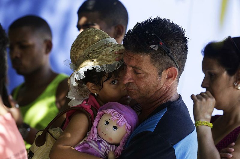Cuban Denis Gomez, 45, and his daughter, Dalia Caridad, 4, attend a meeting Friday at a migrant shelter in Panama City concerning the U.S. policy change.