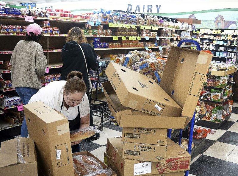 Stephanie Rau restocks bread shelves at Ray’s Green Hills Super Market in St. Joseph, Mo. Ice-storm warnings Friday had people snatching up bread, milk and other staples.