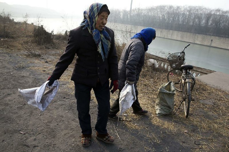 A villager surnamed Shen (right) and a neighbor prepare to pick up coal that fell from overfilled coal trucks rumbling down a bumpy road near the Shougang steel factory in Qianan in northern China’s Hebei province late last month. 