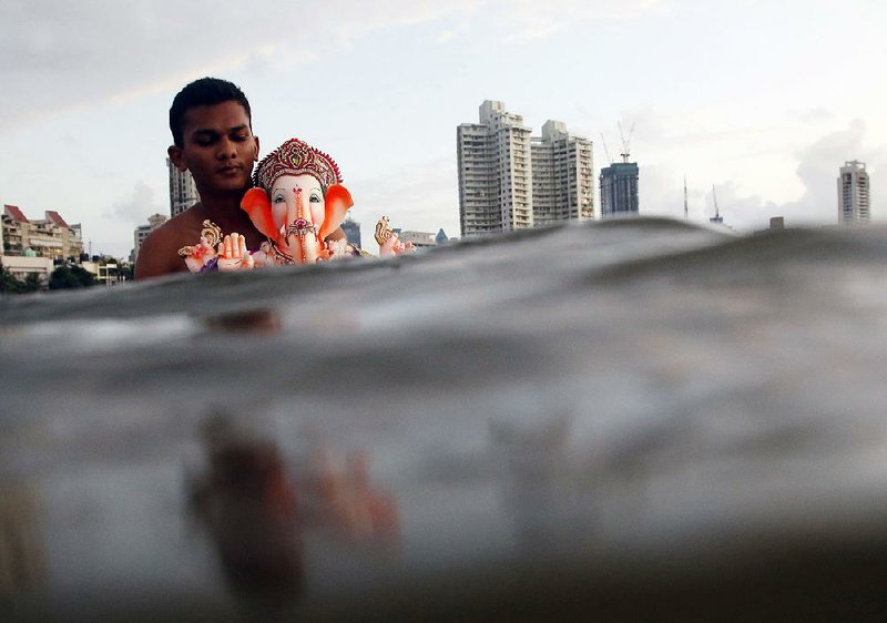 A devotee carries an idol of the elephant-headed Hindu god Ganesha into the Arabian Sea during a festival dedicated to the deity in Mumbai, India. Hindu activists are asking businesses to stop using depictions of Ganesha and other Hindu deities on products, including doormats and toilet seats.