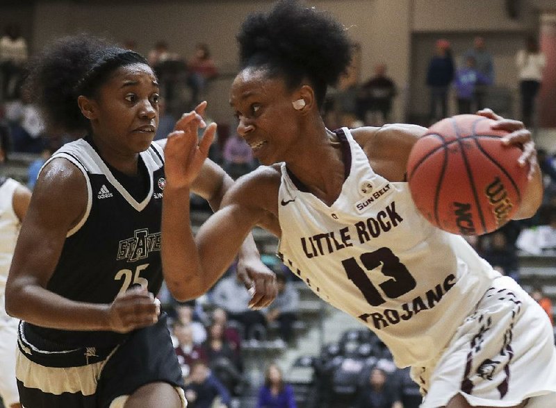 UALR guard Sharde Collins (right) dribbles around ASU defender Dominique Oliver during the Trojans’ 73-59 victory Saturday at the Jack Stephens Center in Little Rock. 