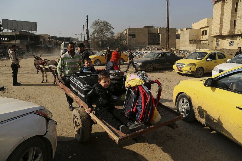 Taxis wait as civilians leave their neighborhoods Monday in Mosul, Iraq, during continued fighting.

