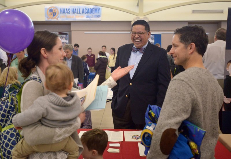 John Rocha, Ozark Catholic Academy head, talks to Mundo Harbaugh (right) and wife Jennifer Harbaugh with sons Henry Harbaugh, 4, and Leo Harbaugh, 15 months, of Rogers on Saturday during the Northwest Arkansas School Choice festival at the Jones Center in Springdale. The academy plans to open in the fall of 2018 in the Springdale or Tontitown area. The event, held as part of National School Choice Week, was an opportunity for families to learn about Northwest Arkansas private, public and charter schools, home-school groups and other education resources.