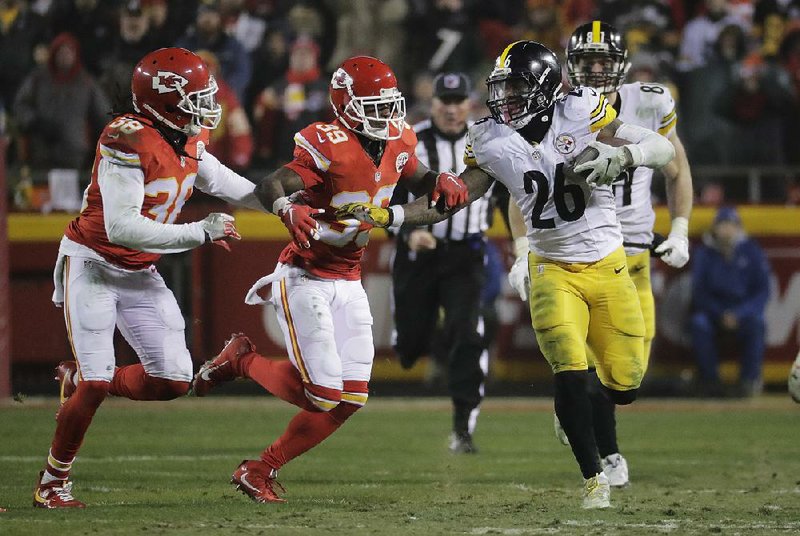 Pittsburgh running back Le’Veon Bell (right) shoves off Kansas City defensive back Terrance Mitchell in Sunday night’s AFC divisional playoff game. Bell ran for 170 yards to help the Steelers hold on to eliminate the Chiefs 18-16.
