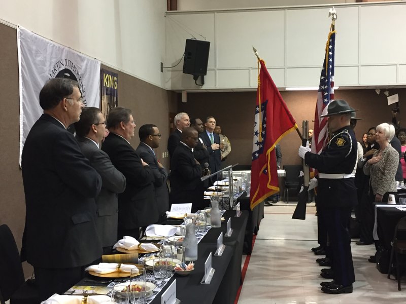 Gov. Asa Hutchinson and other state and local officials stand for the presentation of colors at an interfaith prayer breakfast to honor Martin Luther King Jr. 