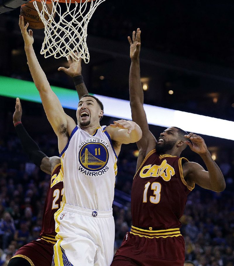 Golden State guard Klay Thompson (left) goes in for a lay-up while Cleveland forward Tristan Thompson chases him from behind during Monday night’s game. Thompson scored 26 points to power the Warriors to a 126-91 rout of the defending NBA champions.