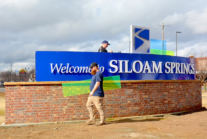 Janelle Jessen/Herald-Leader Henry Mitchell, Tim Stone and William Blackfox (not pictured) worked on Monday morning installing colorful panels on the new Welcome to Siloam Springs sign, located at the intersection of U.S. Highway 412 and Main Street.