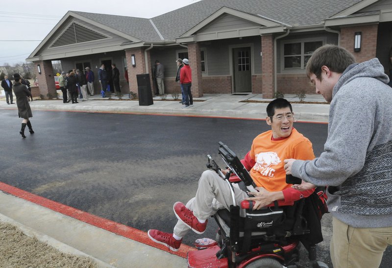 NWA Democrat-Gazette/FLIP PUTTHOFF Andy Tu (left) looks at pictures Chris Costes took Tuesday of the units built by Bost. The units offer housing for people with disabilities.