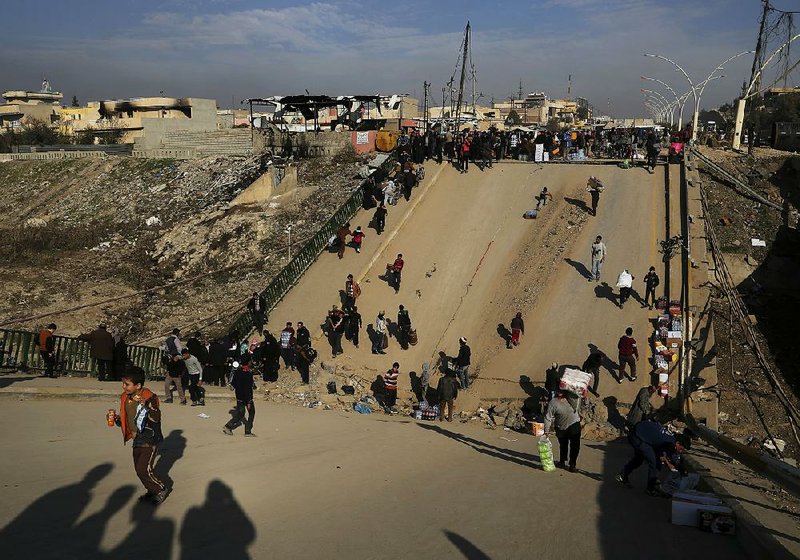 Iraqis on Wednesday cross a bridge destroyed by Islamic State militants in a neighborhood in eastern Mosul recently liberated by government troops.