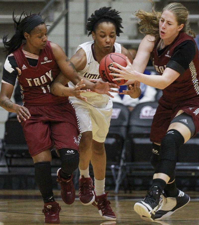 UALR guard Kyra Collier (center) tries to track down a loose ball before Troy defenders ArJae Saunders (left) and Kristen Emerson get to it during Thursday night’s game at the Jack Stephens Center in Little Rock. Collier had 14 points in the Trojans’ 77-74 victory.