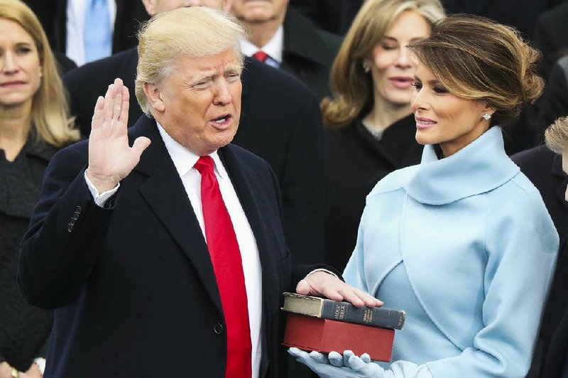 Donald Trump, with his hand on two Bibles held by his wife, Melania, is sworn into office Friday in Washington. One Bible is his own. The other was used by Abraham Lincoln in 1861.