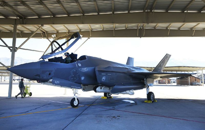 A fighter pilot sits in the cockpit while a crew member checks the exterior of a Lockheed Martin Corp. F-35A jet before a training flight at Hill Air Force Base, Utah, in October 