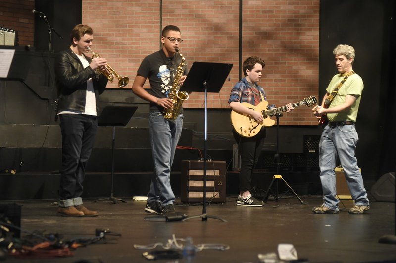 David Singleton (right), Arkansas Arts Academy guitar instructor, works Wednesday with students (from left) Duke Wells, sophomore; Andrew Sweet, sophomore; and Eli Marks, senior, as they practice for a coming concert in Rogers. The school plans to switch to a continuous learning calendar for the 2017-18 school year.