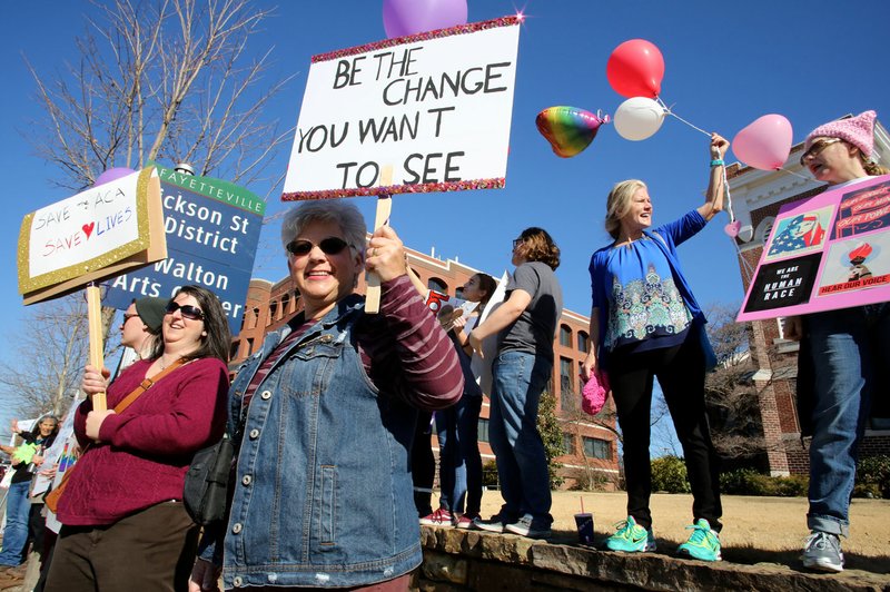 Laurie Spinks (center), from Casseville, Mo., stands Friday with hundreds of demonstrators in front of the Washington County Courthouse on College Avenue in Fayetteville as a showing of solidarity after a divisive election culminating with President Donald Trump’s inauguration. The group of mostly women held balloons and signs expressing ideas of acceptance and equal rights.