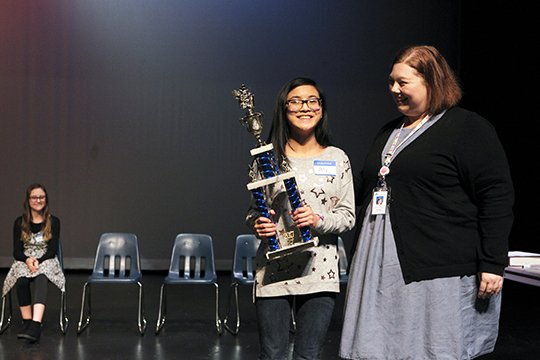The Sentinel-Record/Richard Rasmussen W-I-N-N-E-R: Garland County Spelling Bee coordinator Amanda Bradley, right, presented Lakeside High School eighth-grader Aly Navarro with the first place trophy Friday morning in the Jessieville School District Performing Arts Center. Navarro is the sister of the winner of the past three county spelling bees, A.J. Navarro.