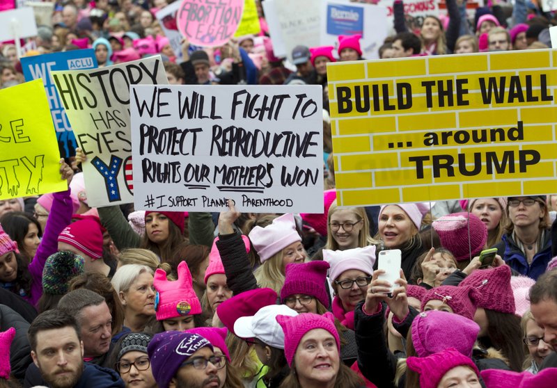 Women with bright pink hats and signs begin to gather early and are set to make their voices heard on the first full day of Donald Trump's presidency, Saturday, Jan. 21, 2017 in Washington.