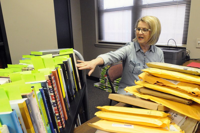 Cherie Geiser, a volunteer with the Benton County Literacy Council, sorts through some of the hundreds of signed books donated by authors that will be sold at auction during “Scrabble Wars,” a fundraiser for the council.