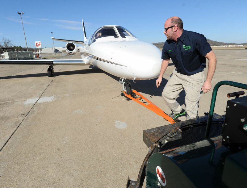 Matthew Atkinson, airport operations supervisor for Fayetteville, demonstrates the use of a tug Friday to move a private jet along the tarmac at Fayetteville Executive Airport.